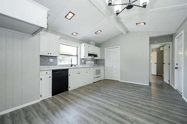 a kitchen with a sink cabinets stainless steel appliances and wooden floor