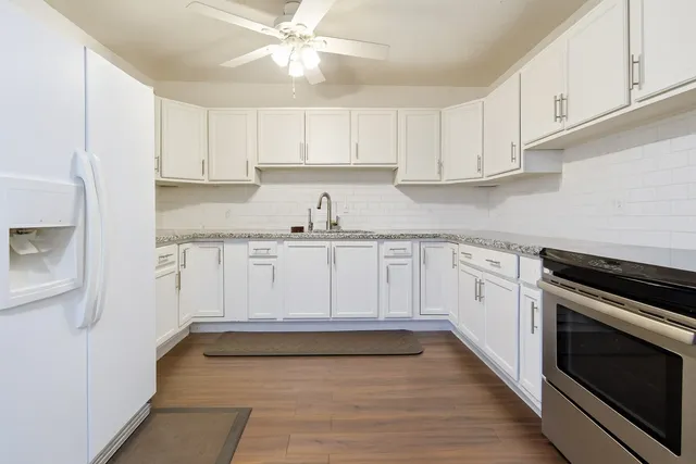 a kitchen with granite countertop white cabinets and white appliances