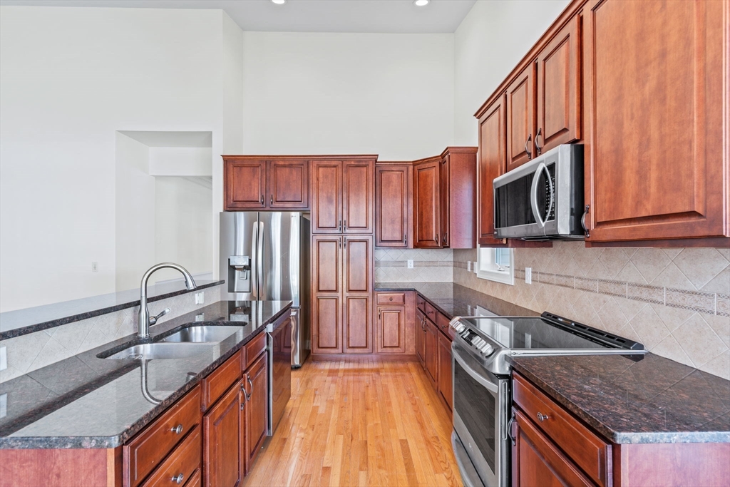 11 Pondside Lane, Unit 11 Bolton, MA 01740 - Photo 17 of 29 a kitchen with stainless steel appliances granite countertop a sink stove and refrigerator