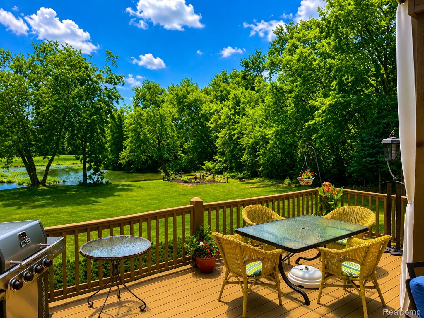 2495 North Custer Road Monroe, MI 48162 - Photo 35 of 44 Spacious wood-finish deck overlooking a verdant lawn and natural water feature
