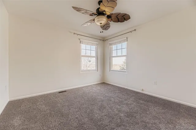 an empty room with windows and ceiling fan