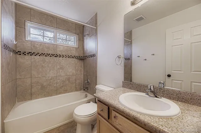 a bathroom with a granite countertop sink a toilet and bathtub