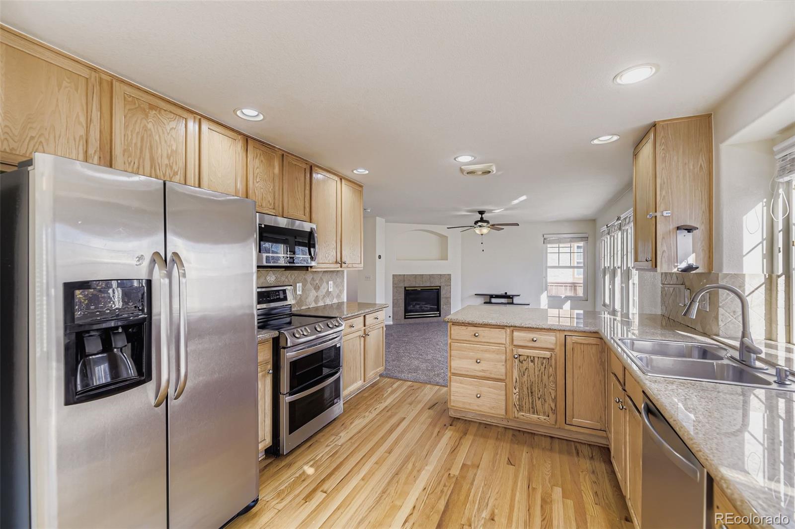 2430 South Jebel Way Aurora, CO 80013 - Photo 7 of 28 a large kitchen with stainless steel appliances granite countertop a refrigerator a stove and a sink with wooden floor