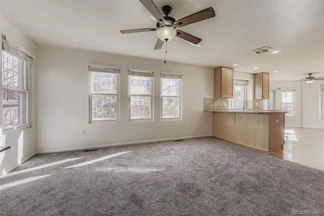 an empty room with windows and ceiling fan