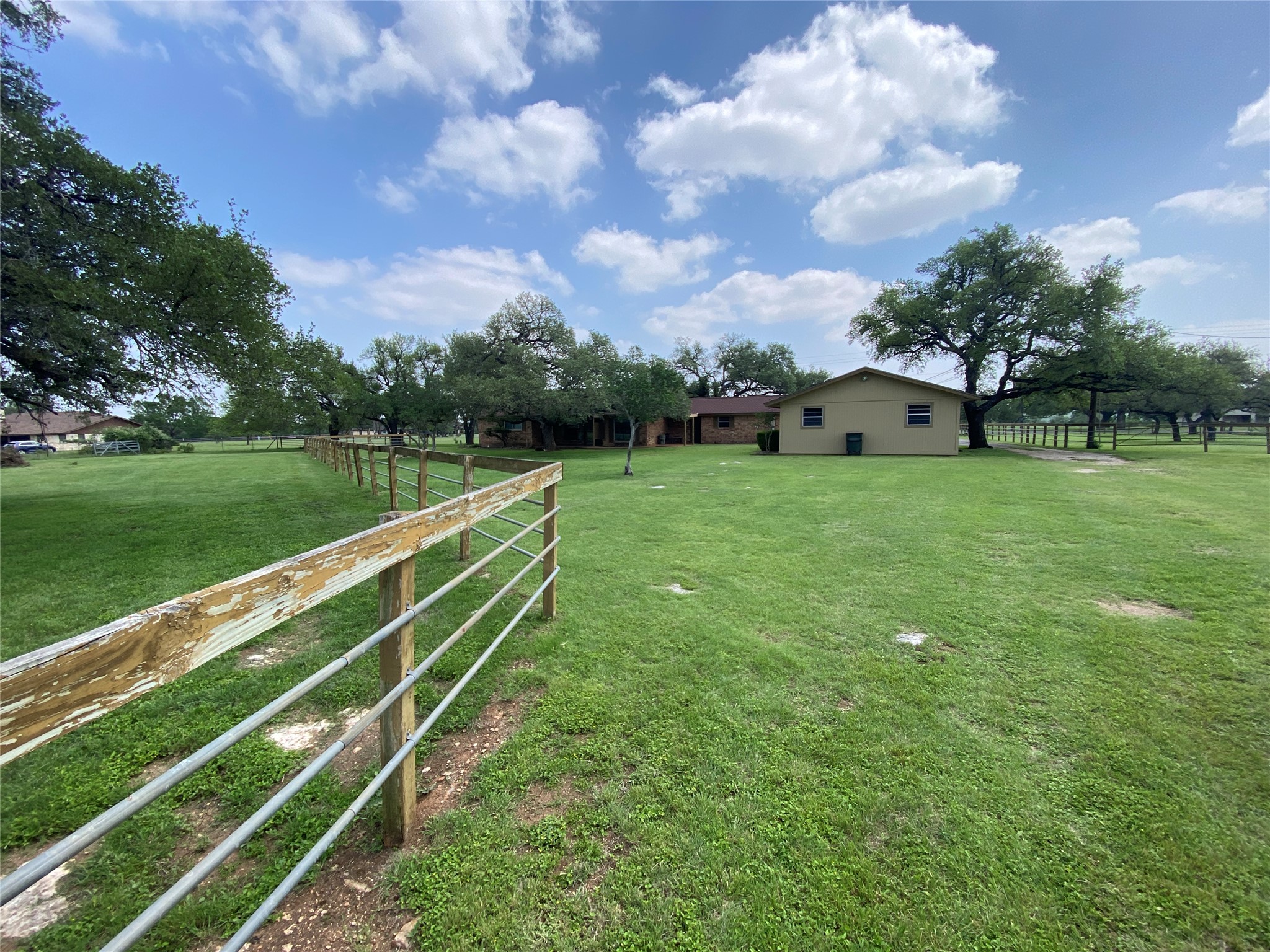 140 Oak Ridge Road Georgetown, TX 78628 - Photo 17 of 40 Expansive green lawn with mature trees and a perimeter fence with wood posts and metal rails