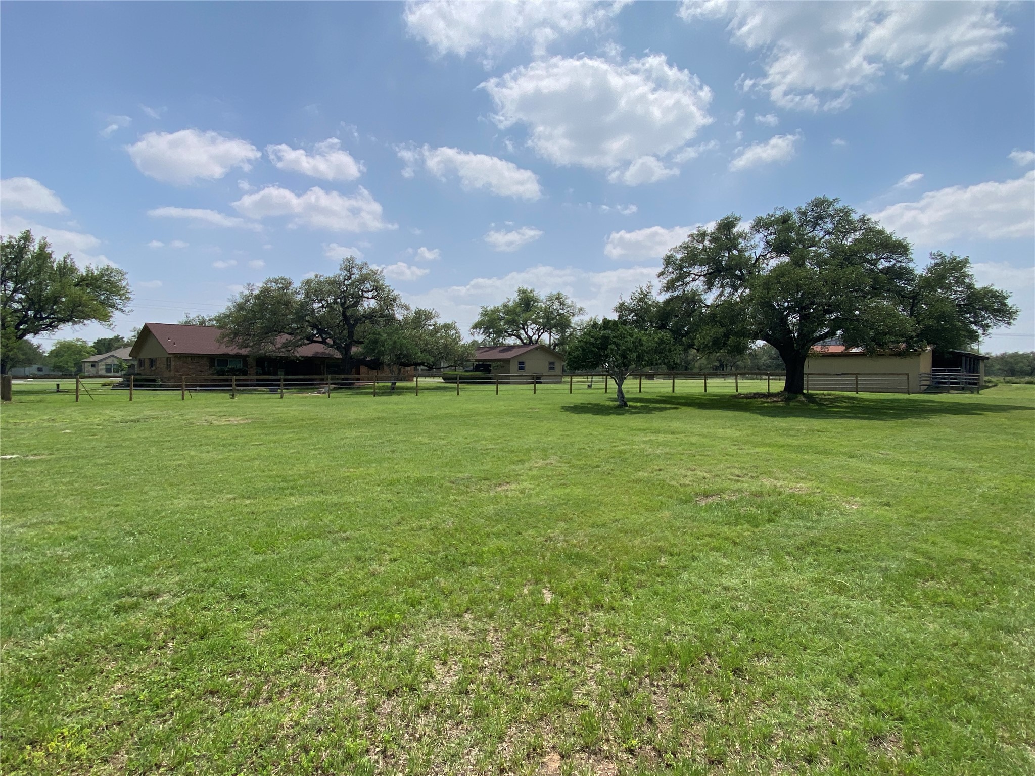 140 Oak Ridge Road Georgetown, TX 78628 - Photo 20 of 40 Expansive green lawn with mature trees and a distant single-story residence featuring a covered porch