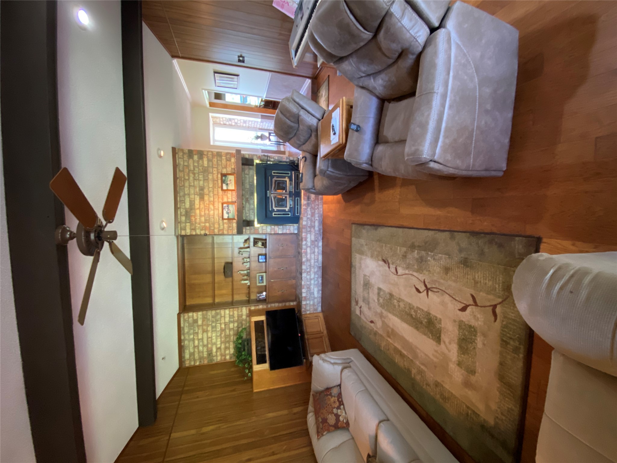 140 Oak Ridge Road Georgetown, TX 78628 - Photo 31 of 39 Living area with wood walls, a fireplace, beam ceiling, wood finished floors, and ceiling fan