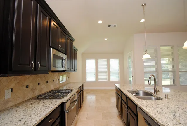 a kitchen with granite countertop a sink a stove and cabinets