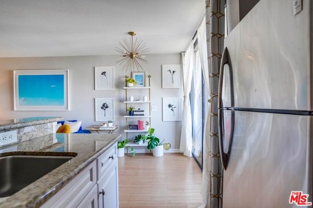 a kitchen with stainless steel appliances a sink a faucet a chandelier and refrigerator