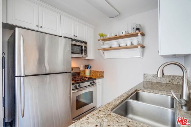 a kitchen with a refrigerator sink and white cabinets