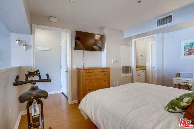 a bedroom with a bed and a flat tv screen on a dresser