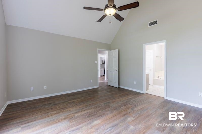 101 Lawson Road Daphne, AL 36526 - Photo 7 of 20 Spacious room featuring vaulted ceilings, wood-finish flooring, a ceiling fan with integrated lighting, and neutral wall paint