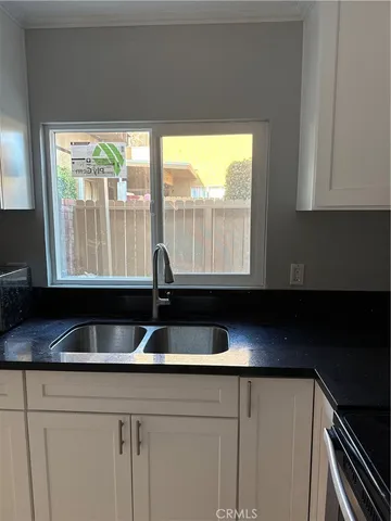 a kitchen with granite countertop a sink and a white wooden cabinets