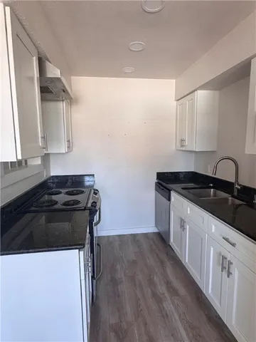 a kitchen with granite countertop a sink stove and cabinets