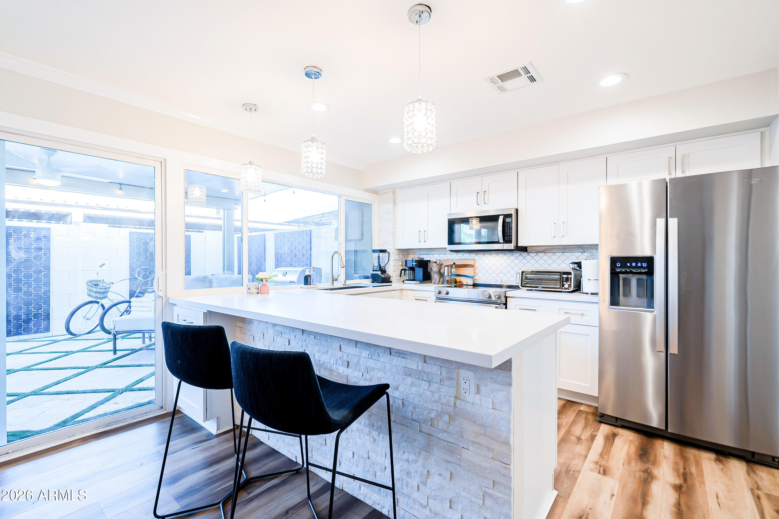 4243 North Miller Road Scottsdale, AZ 85251 - Photo 7 of 24 a kitchen with stainless steel appliances granite countertop a refrigerator a sink dishwasher a stove and white cabinets with wooden floor