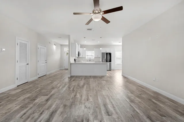a view of kitchen and empty room with wooden floor
