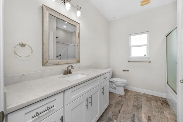 a bathroom with a granite countertop toilet sink and mirror