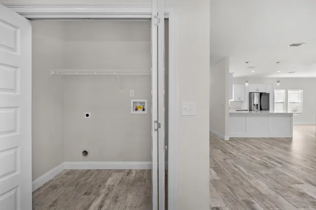 a view of empty room with wooden floor and kitchen