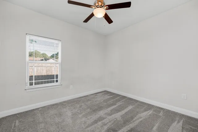 an empty room with a window and a fan