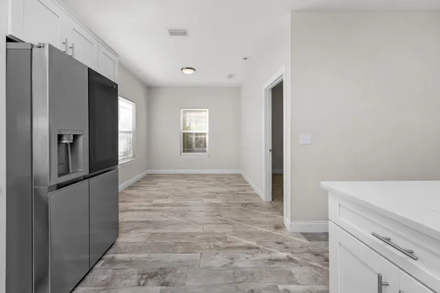 a view of hallway with window and wooden floor