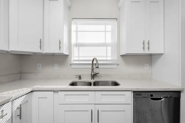 a kitchen with white cabinets and a window