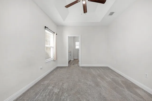 an empty room with ceiling fan and windows