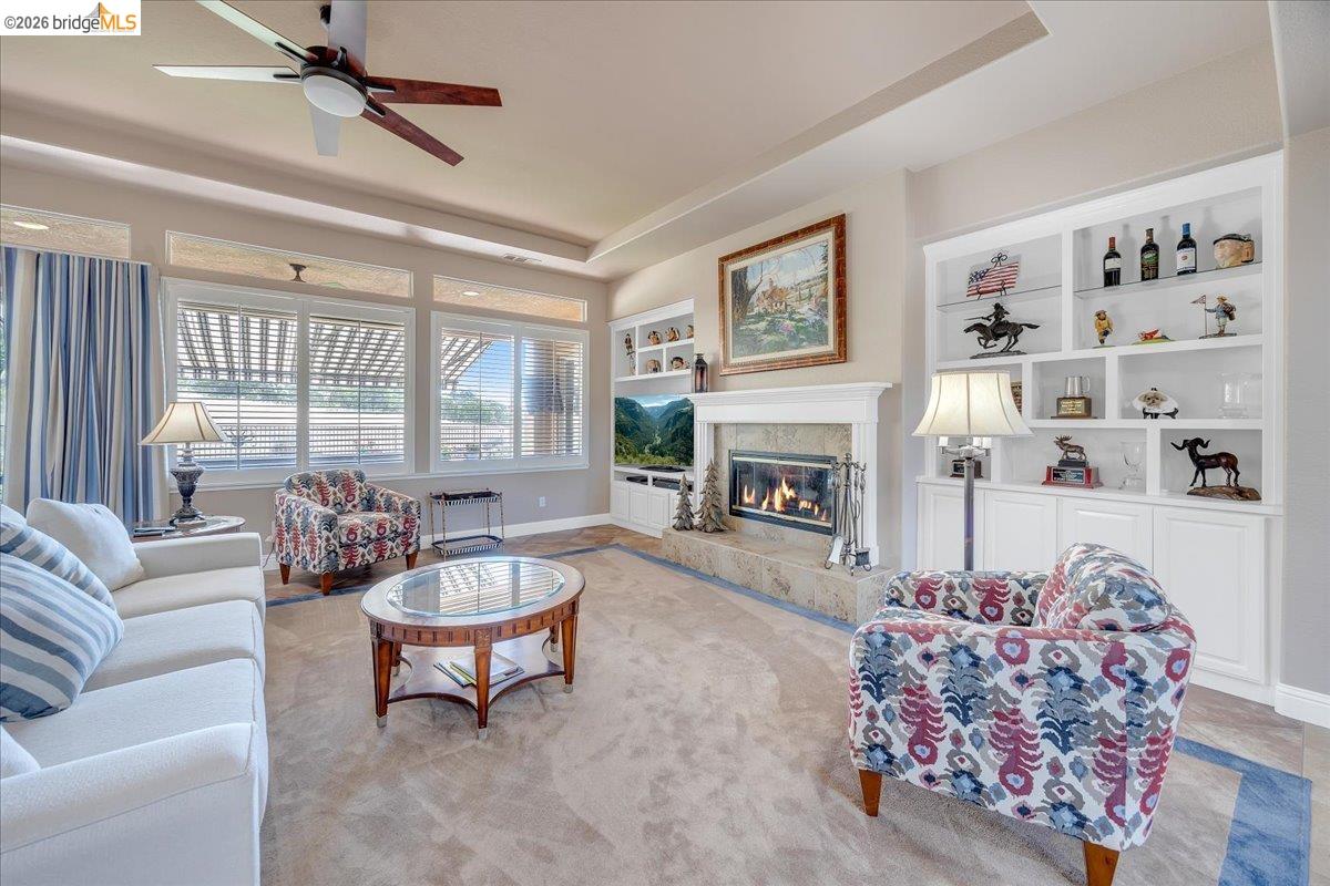 158 Rock Ridge Lane Copperopolis, CA 95228 - Photo 12 of 72 Living area featuring a central fireplace with a stone surround and white mantel, flanked by built-in shelving and cabinetry