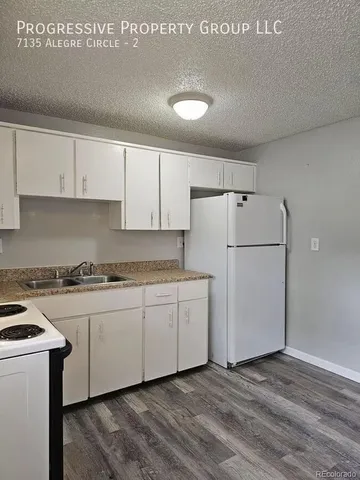 a kitchen with granite countertop white cabinets and white appliances
