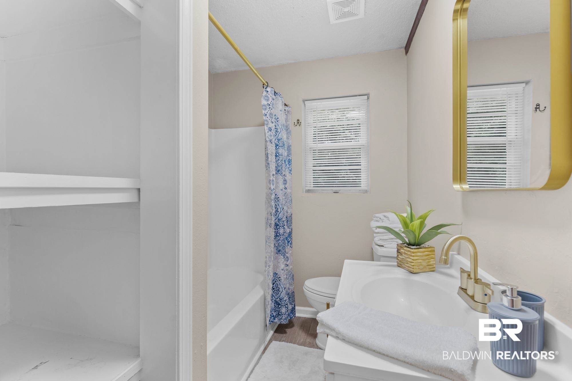 1560 Military Road Mount Vernon, AL 36560 - Photo 24 of 26 Bathroom featuring a window with blinds, white vanity with integrated sink, gold-finish faucet, and built-in shelving