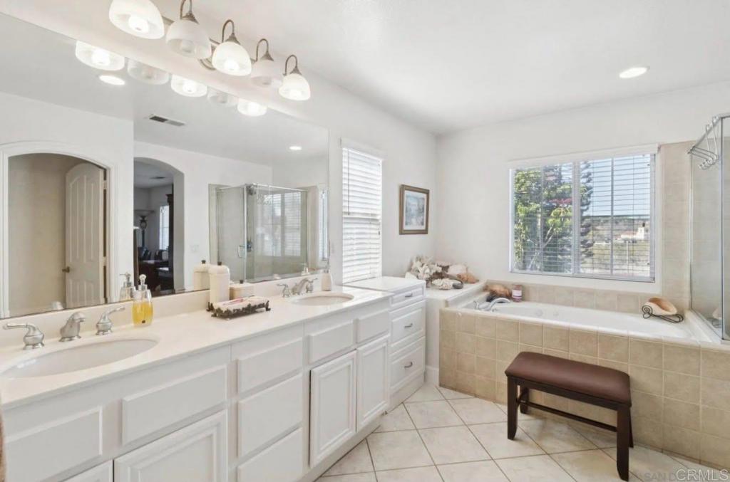 1234 Old Janal Ranch Road Chula Vista, CA 91915 - Photo 29 of 34 a bathroom with a granite countertop sink a large mirror a bathtub and next to a window