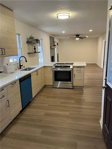 a large kitchen with stainless steel appliances a large counter top a stove a sink and a refrigerator