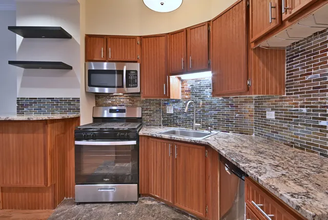 a kitchen with stainless steel appliances granite countertop wooden cabinets a stove and a sink