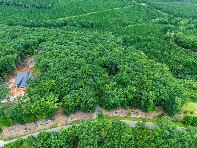 an aerial view of residential house with outdoor space and trees all around