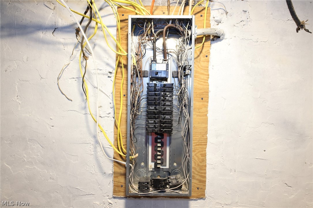 416 5th Street Chester, WV 26034 - Photo 21 of 24 Electrical service panel mounted on a plywood backer board with exposed wiring and a textured white wall