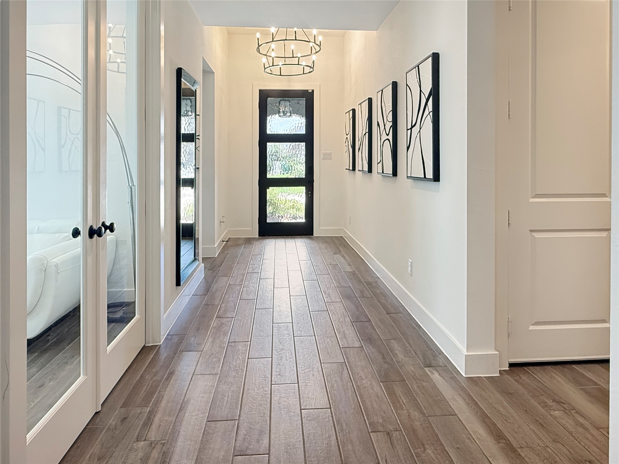 26918 Swanborough Road Spring, TX 77389 - Photo 6 of 50 A statement chandelier and seeded-glass front door set an elegant tone from the moment you step inside, with rich wood-look tile flooring guiding you through the gallery hallway.