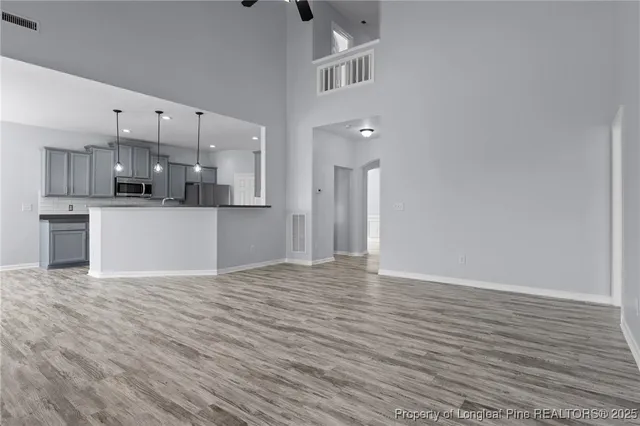 a view of a kitchen with kitchen island wooden floor and stainless steel appliances