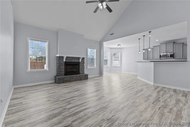an empty room with wooden floor kitchen view and a window
