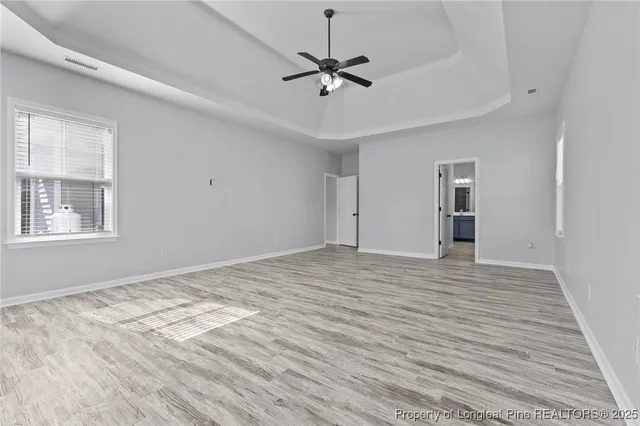 a view of empty room with wooden floor and ceiling fan