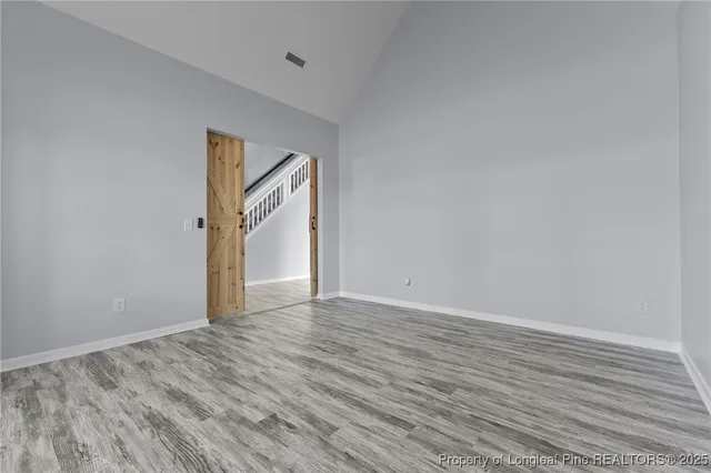 a view of an empty room with wooden floor and window
