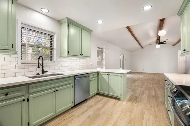 a kitchen with a sink a counter space appliances and cabinets