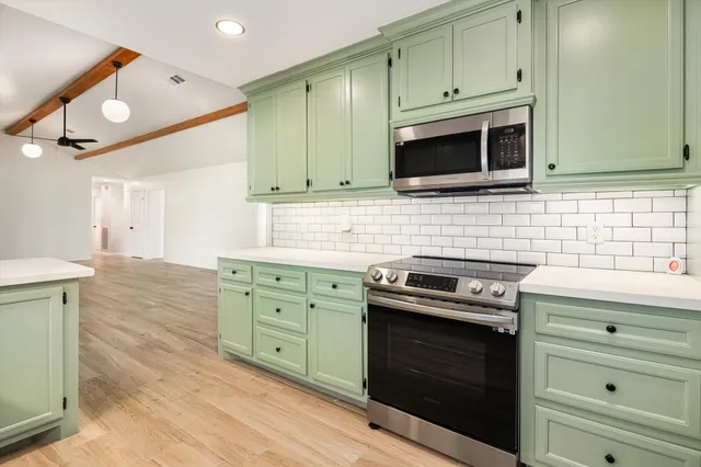 a kitchen with granite countertop cabinets stainless steel appliances and wooden floor