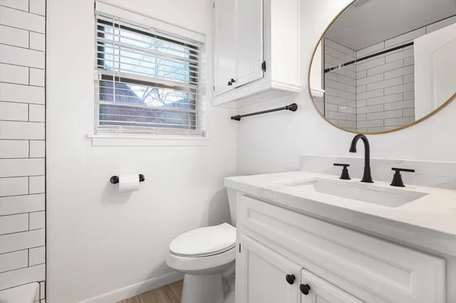 a bathroom with a granite countertop toilet sink and mirror