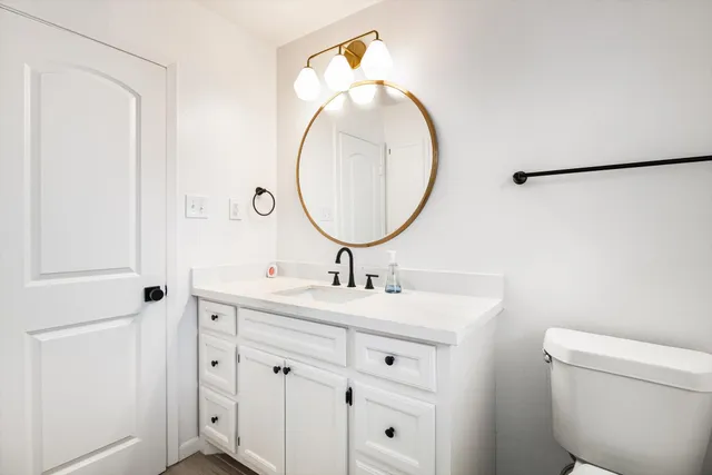 a bathroom with a sink mirror vanity and toilet