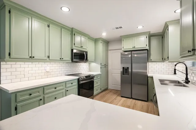 a kitchen with stainless steel appliances granite countertop a sink a stove a refrigerator and cabinets