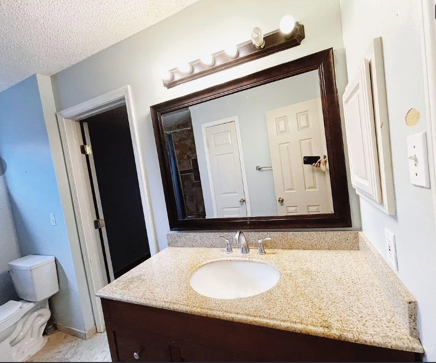 1906 Woodstream Boulevard Sugar Land, TX 77479 - Photo 11 of 14 a bathroom with a granite countertop sink and a mirror