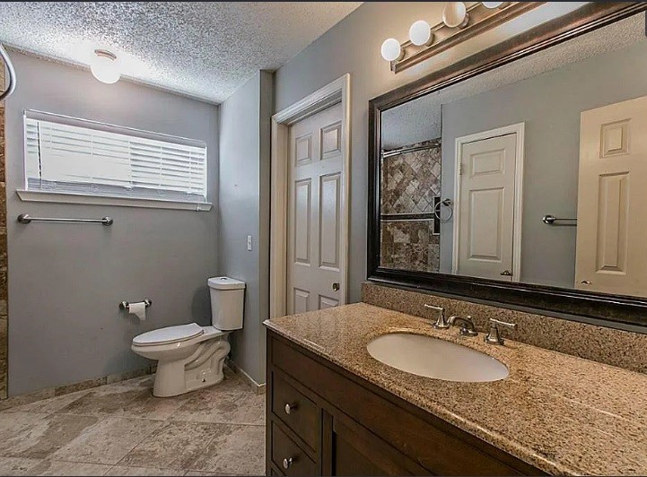 1906 Woodstream Boulevard Sugar Land, TX 77479 - Photo 10 of 14 a bathroom with a granite countertop toilet a sink and a mirror