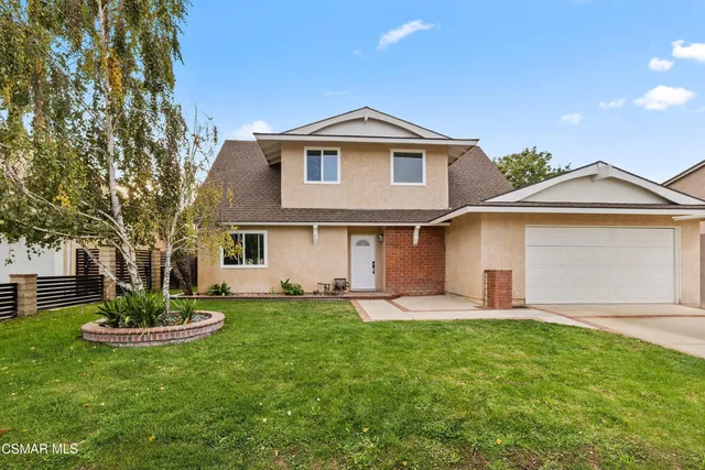 a front view of a house with a garden and trees
