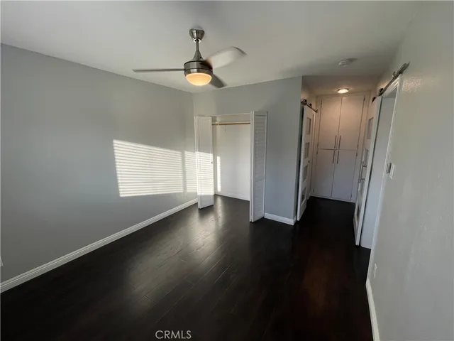 a view of empty room with wooden floor and fan