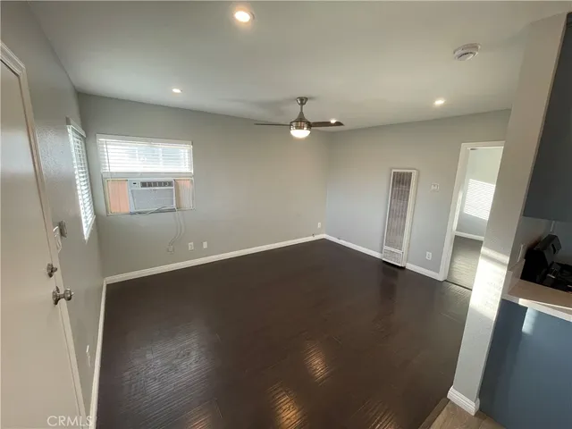 an empty room with wooden floor and a ceiling fan