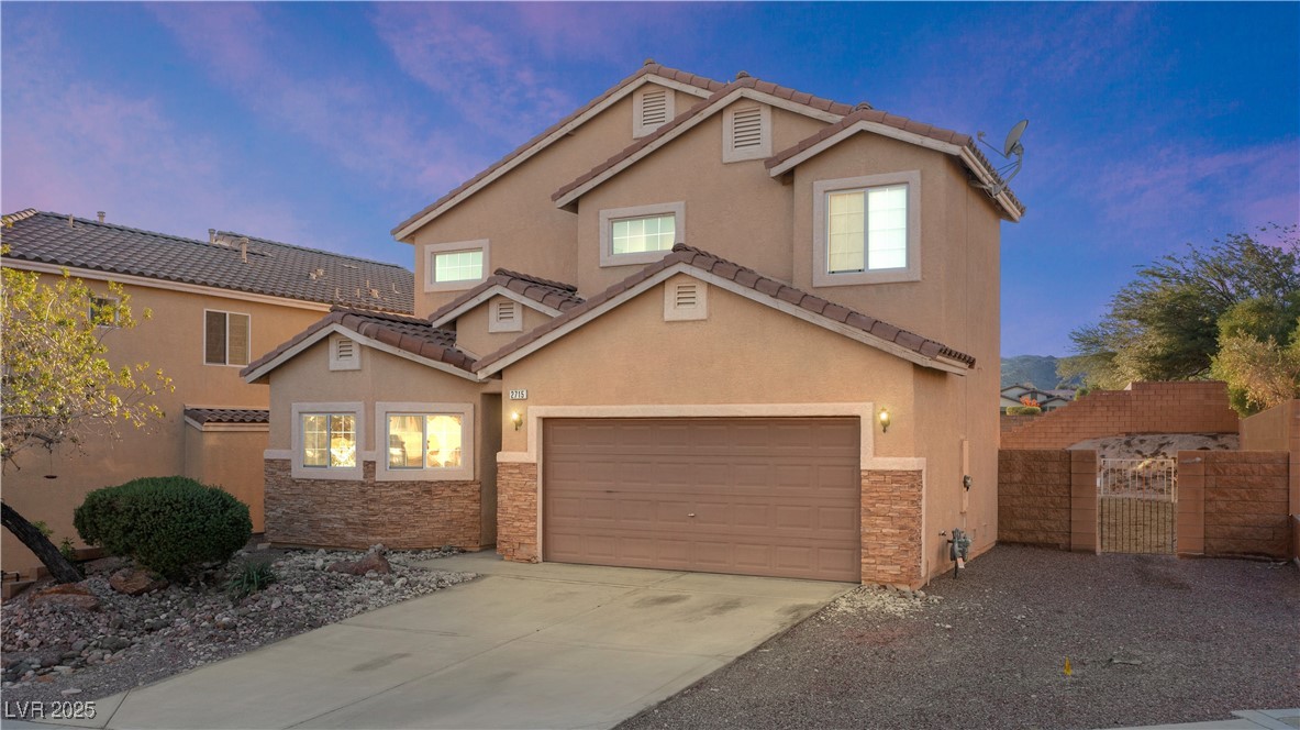 View of front facade featuring a gate, stone siding, and stucco siding